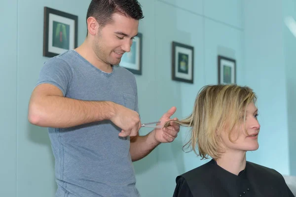 Cabeleireiro masculino faz o corte para a menina loira cabeleireiro masculino — Fotografia de Stock
