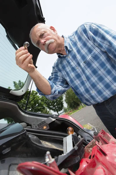 Elder man servicing his car at home — Stock Photo, Image