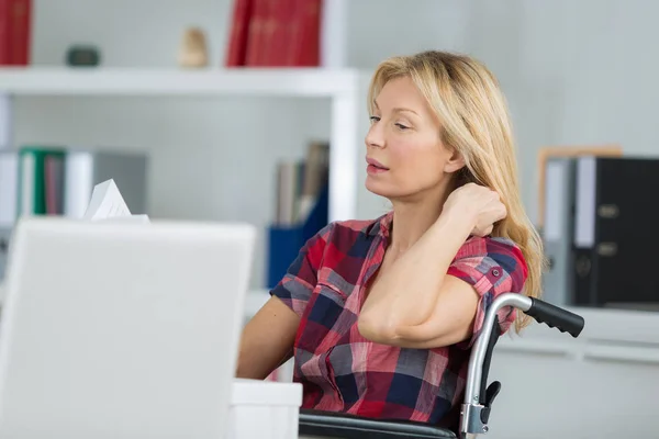 Evde dizüstü bilgisayar kullanan tekerlekli sandalyedeki engelli kadın. — Stok fotoğraf
