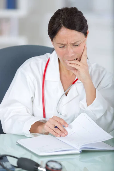 Thoughtful female doctor holding a file — Stock Photo, Image