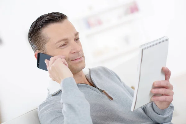 Attraente uomo d'affari sorridente prendere appunti parlando al telefono — Foto Stock