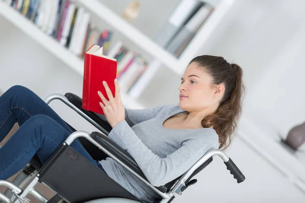 Девушка в инвалидном кресле с книгой — стоковое фото