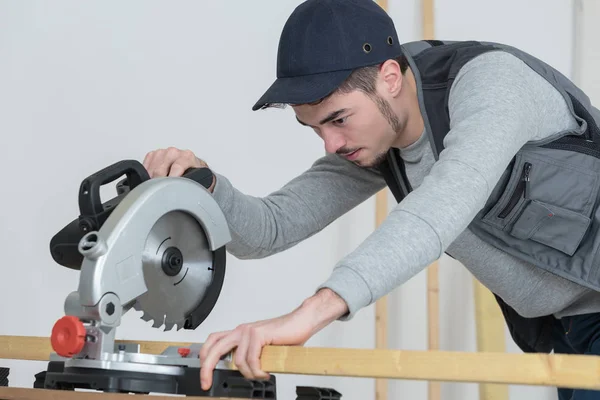 Man lowering circular saw to wood