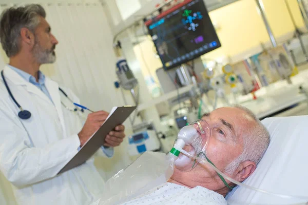 Arzt notiert Patientendaten vom Monitor — Stockfoto