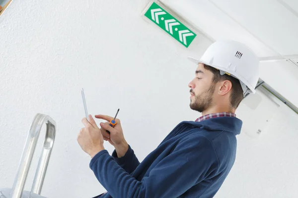 Mannelijke elektricien permanent op trapladder herstellen licht — Stockfoto