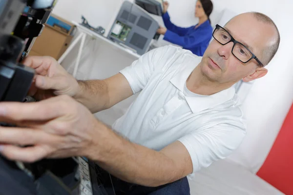 Técnico sênior masculino está reparando uma impressora no escritório — Fotografia de Stock