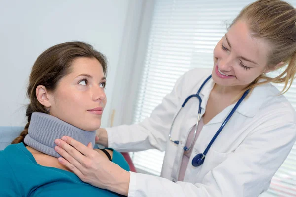 Sonriente médico femenino ajustando la abrazadera del cuello en bastante paciente —  Fotos de Stock