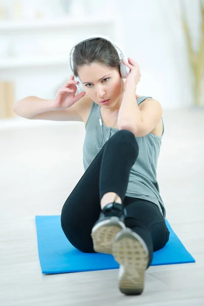 Young woman working out on exercise mat at home — Stock Photo, Image