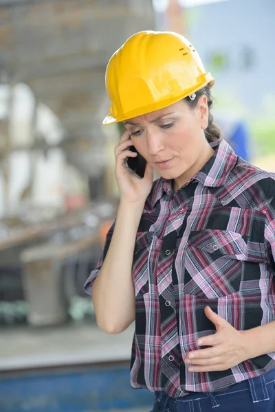工業地帯で携帯電話で話す女性労働者 — ストック写真