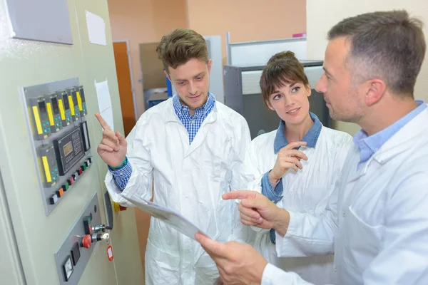 Cientista e aprendiz fazendo leituras de máquinas eletrônicas — Fotografia de Stock