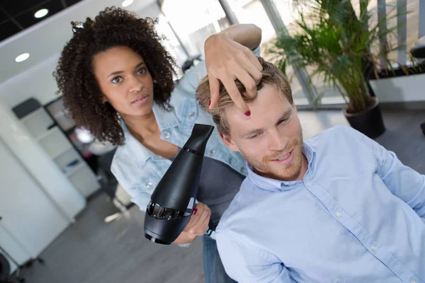 Peluquería femenina secando su cabello clientes masculinos — Foto de Stock