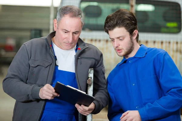 Manager van de fabriek en leerling ingenieur kijken naar Klembord — Stockfoto