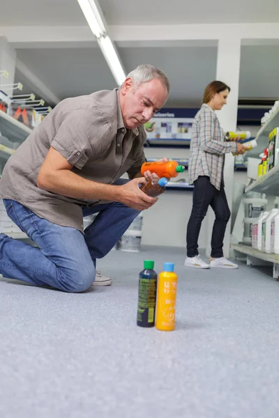 Hombre eligiendo productos químicos domésticos en el supermercado — Foto de Stock