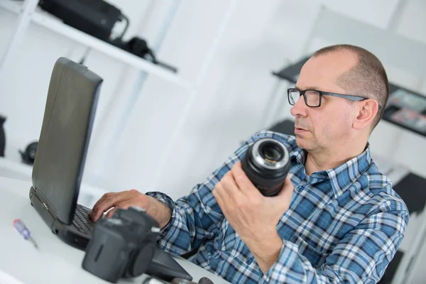 Technician repairing broken digital camera lense in his workshop — Stock Photo, Image
