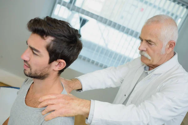 Chiropraktiker arbeitet am Rücken des jungen Mannes — Stockfoto