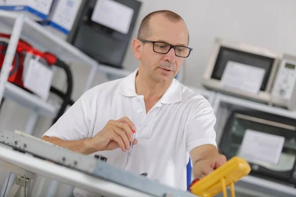 Nahaufnahme eines Mannes, der einen Gegenstand mit einem Multimeter repariert — Stockfoto