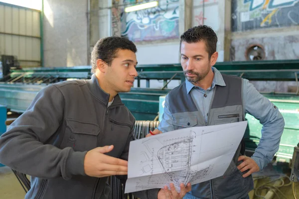 Män i fabriken tittar på planer — Stockfoto