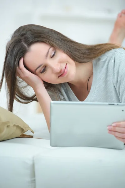 Lachende jonge vrouw op de bank kijken naar laptop vaststelling — Stockfoto