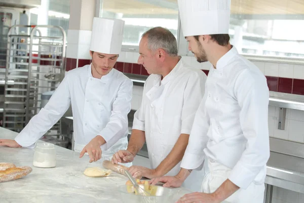 Maschio panettiere mostrando i suoi apprendisti i segreti della pasticceria — Foto Stock