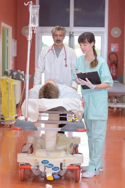 Persone con uniformi mediche che trasportano un paziente in chirurgia — Foto Stock