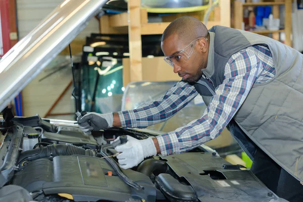 Mechanik naprawy silnika samochodu w swoim warsztacie — Zdjęcie stockowe