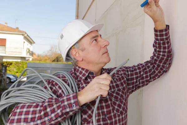 Elektriker findet ein Loch, um eine Verkabelung einzuführen — Stockfoto