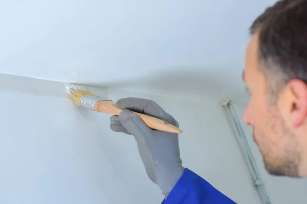 Homme avec pinceau peignant le plafond d'une maison — Photo