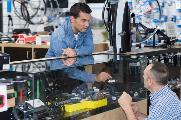 Vendedor na loja de bicicletas assessorando cliente — Fotografia de Stock