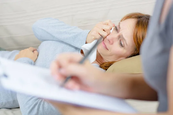 Frau fühlt sich beim Telefonieren auf dem Sofa unwohl — Stockfoto