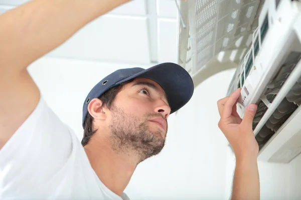 Jeune homme nettoyage système de climatisation — Photo