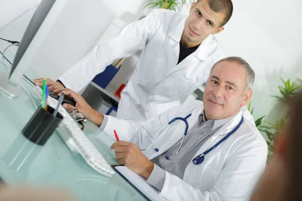 Doctor hablando con un paciente con su joven asistente —  Fotos de Stock