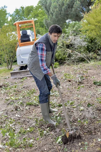 Mann arbeitet im Garten, Bagger im Hintergrund — Stockfoto