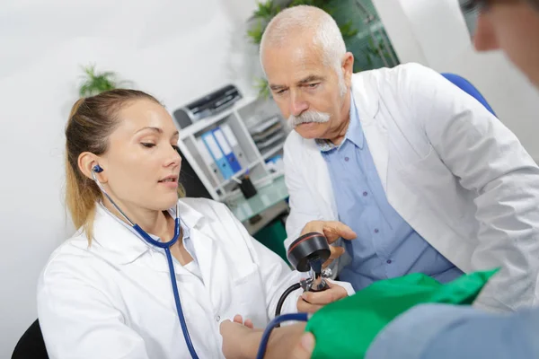 Médico que mede a pressão arterial para fazer um diagnóstico — Fotografia de Stock