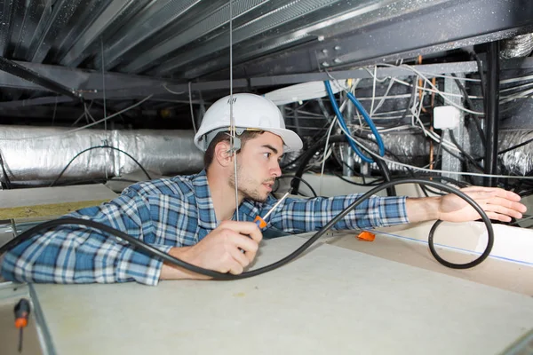 Giovane elettricista fissaggio neon sul soffitto — Foto Stock