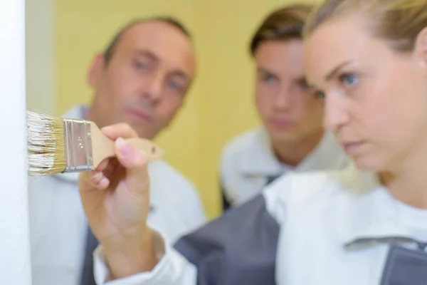 Vrouw schilderij gadegeslagen door twee mannen — Stockfoto