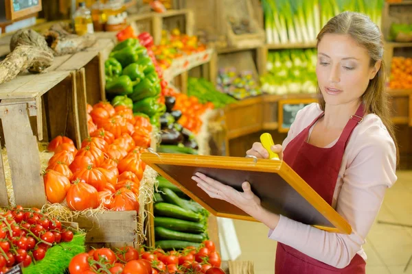 Mulher escrevendo sinal para frutas e vegetais — Fotografia de Stock