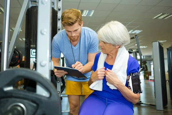 Mujer mayor haciendo ejercicios deportivos con entrenador o entrenador personal —  Fotos de Stock