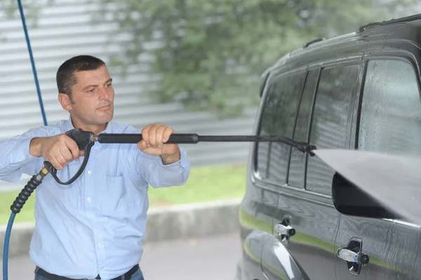 Biltvätt - man arbetar med högtryckstvätt — Stockfoto
