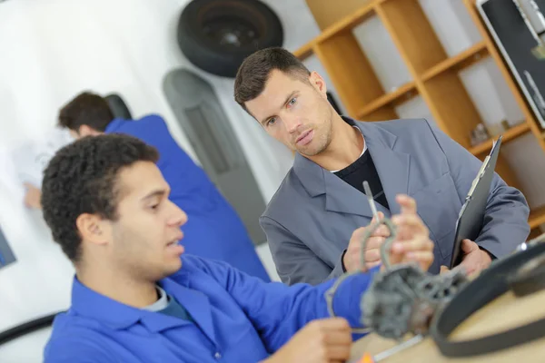 Monteur en leerling werken op auto met computer — Stockfoto