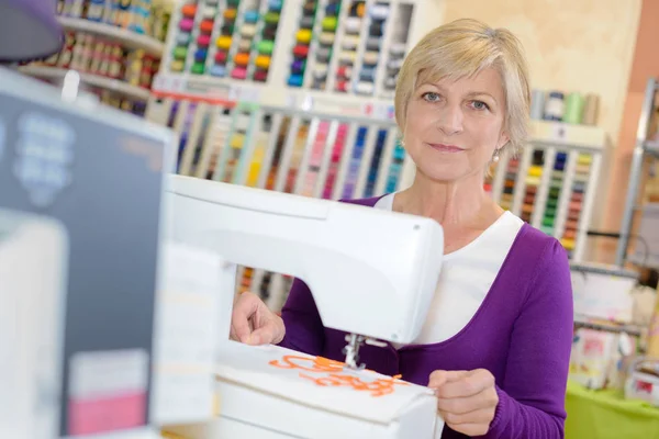 Smiley woman sewing on sewing-machine — Stock Photo, Image