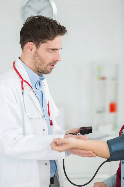 Portrait of happy doctor checking patients blood pressure in clinic — Stock Photo, Image