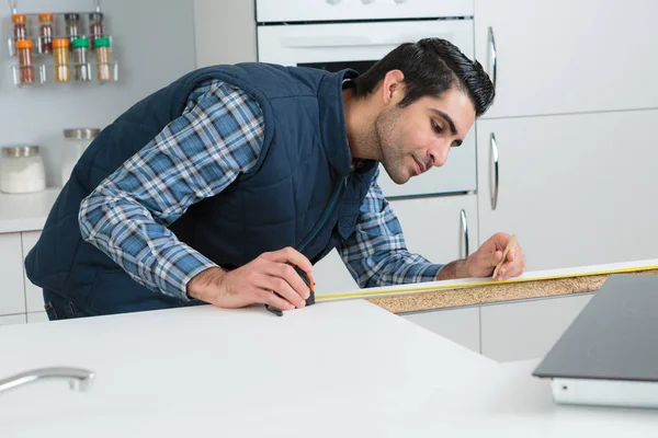 Trabajador calculando medidas en una construcción de cocinas — Foto de Stock