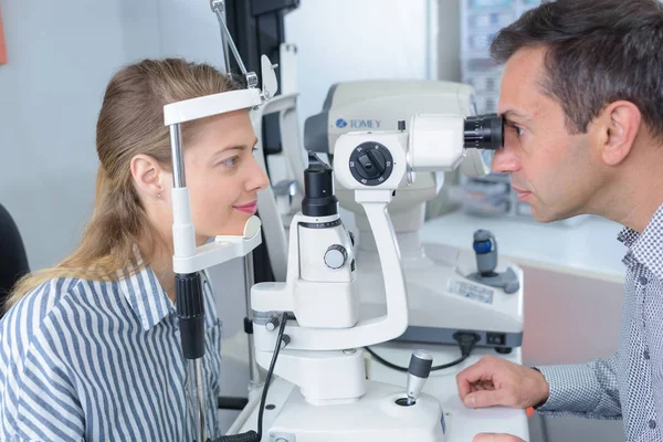 Male optometrist with trial frame checking female patient vision — Stock Photo, Image
