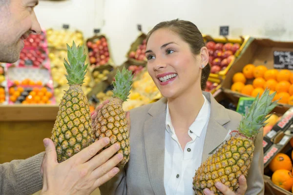 Mujer sonriente eligiendo diferentes frutas en la exhibición de la tienda de alimentos de granja —  Fotos de Stock