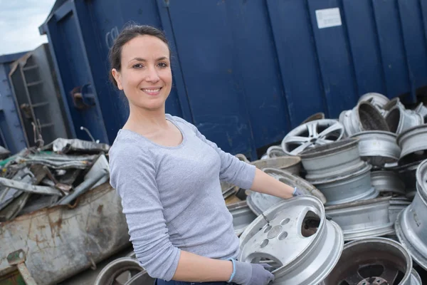 Damen i skrotupplag transporterar fälg — Stockfoto