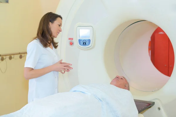 Nurse talking to man entering scanner — Stock Photo, Image