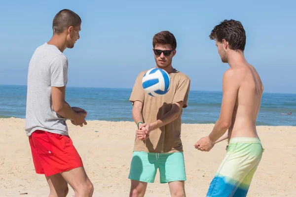 Groep van jeugdvrienden volleyballen op strand — Stockfoto