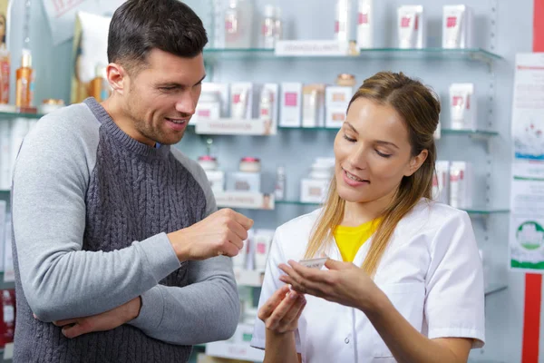 Farmacêutico fêmea aconselhando cliente sobre o uso de drogas — Fotografia de Stock