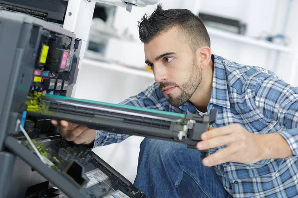 Joven hombre reparar impresora en la oficina moderna — Foto de Stock