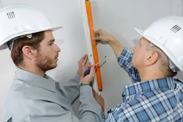 Aprendiz trabalhador da construção civil apoiando-se com comerciante experiente — Fotografia de Stock